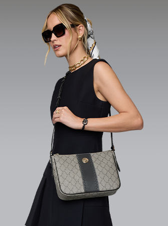 Modelo de vestido preto com bolsa monogramada a tiracolo